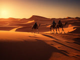 Camel caravan with riders crossing desert dunes in open dune landscape