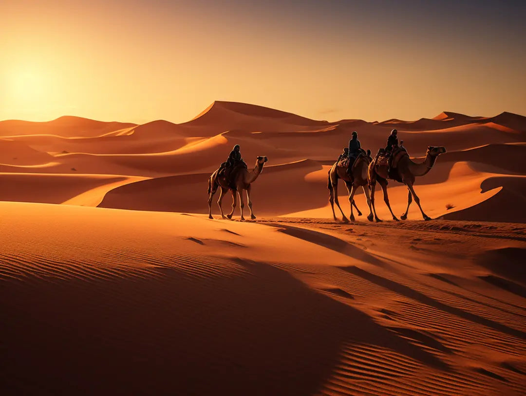 Camel caravan with riders crossing desert dunes in open dune landscape