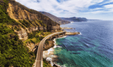 Curving elevated roadway along a rocky coastline in rocky shoreline with an elevated roadway between cliffs and ocean
