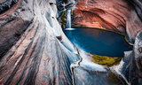 Blue natural pool enclosed by sculpted rock walls in enclosed rock basin or gorge
